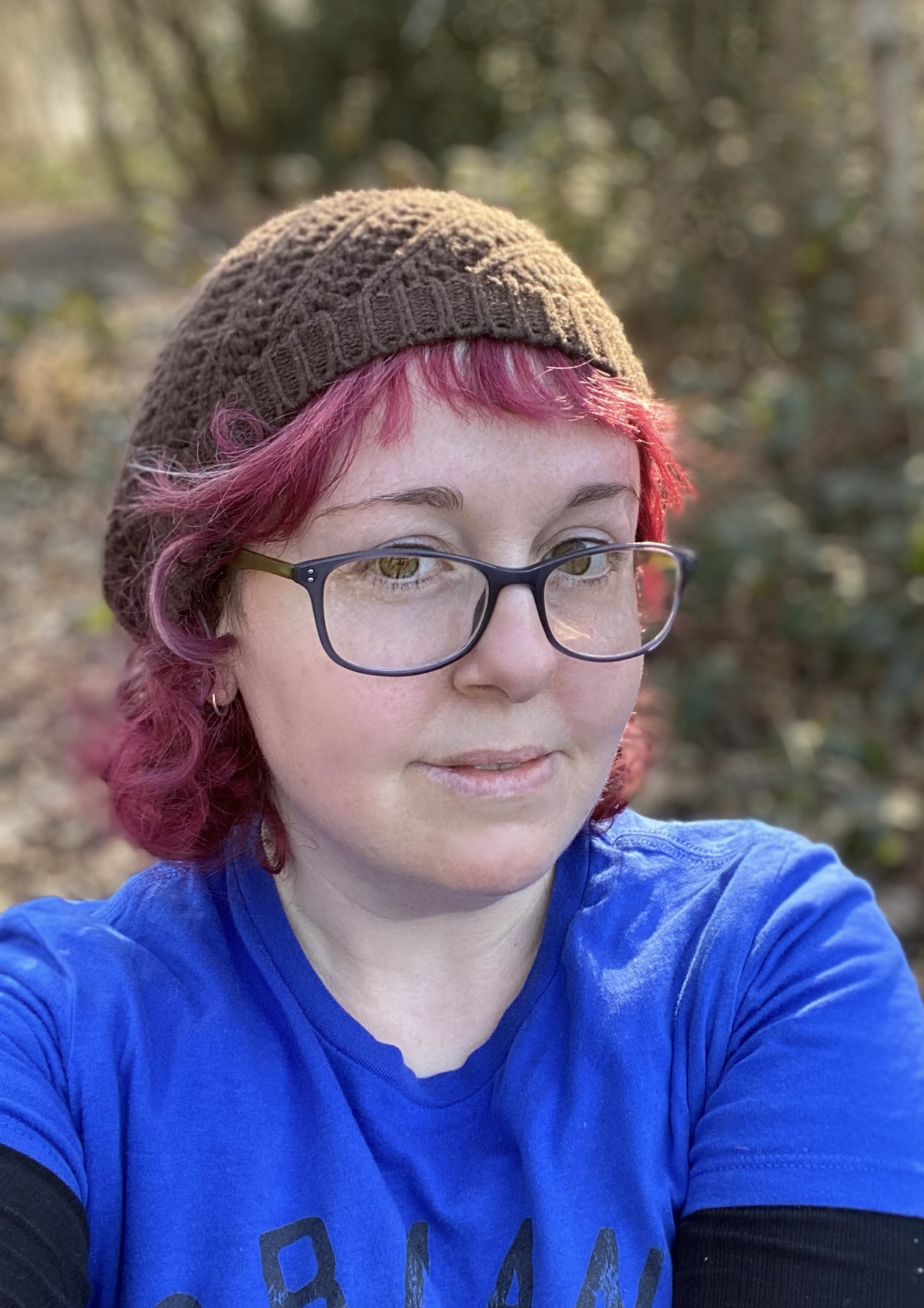 Clare Stark, a white woman with dyed red hair, is smiling at the camera.